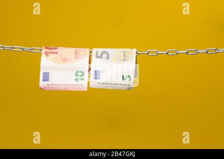 Geld, das in einer Kette gehalten wird oder an einer Kette hing; gesetzliches Zahlungsmittel in Papierform; Euro, Währung der europäischen Wirtschaftsgemeinschaft, Gemeinsamer Markt. Stockfoto