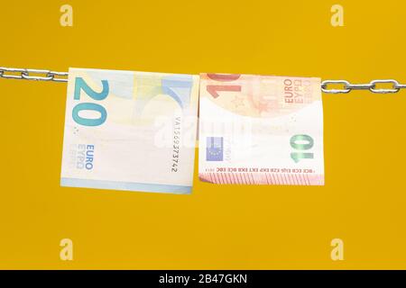 Geld, das in einer Kette gehalten wird oder an einer Kette hing; gesetzliches Zahlungsmittel in Papierform; Euro, Währung der europäischen Wirtschaftsgemeinschaft, Gemeinsamer Markt. Stockfoto