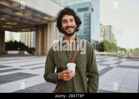 Porträt eines gutaussehenden jungen Geschäftsmannes, der im Freien eine Tasse Kaffee hält Stockfoto