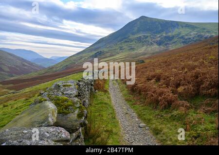 Ein Fußweg folgt der Linie einer trockenen Steinmauer im Lake District, Cumbria, Großbritannien Stockfoto