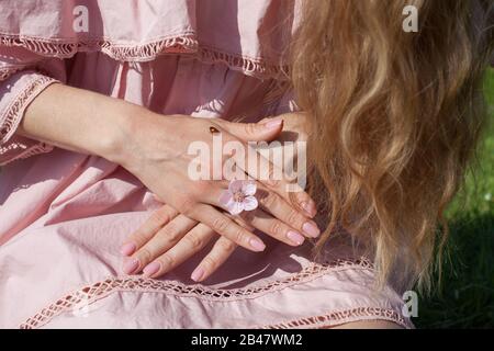 Schöne blonde Frau in rosafarbenem Kleid und Marienkleid an der Hand Stockfoto