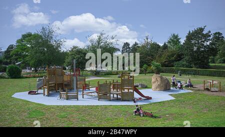 Kinder, die die Spielbereiche im Salt Hill Park, Slough, genießen, während ihre Eltern darauf schauen. Sonniger Tag, Mittsommerurlaub Stockfoto