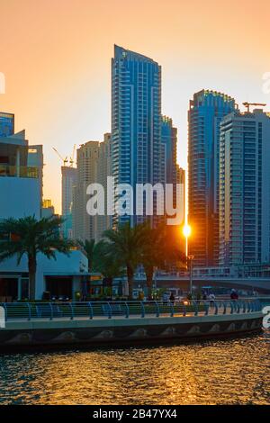 Die Sonne zwischen den Gebäuden von Dubai Marina bei Sonnenuntergang, Vereinigte Arabische Emirate Stockfoto