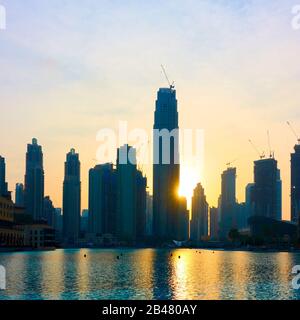 Silhouetten neuer Wolkenkratzer und deren Reflexion im Wasser bei Sonnenuntergang, Dubay City, OAE Stockfoto