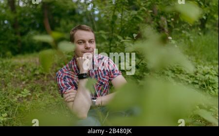 Der junge pensive Mann blickt auf den Fluss. Einheit mit der Natur. Stockfoto