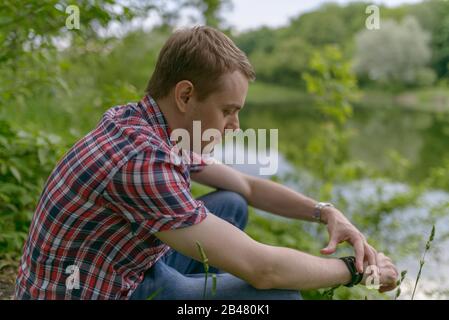 Der junge pensive Mann blickt auf den Fluss. Einheit mit der Natur. Stockfoto