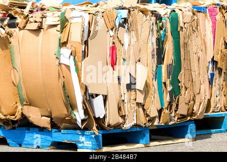 Kartonbündel, die recycelt werden sollen. Pappe wird in Ballen gebündelt. An einem sonnigen Tag ist draußen. Stockfoto