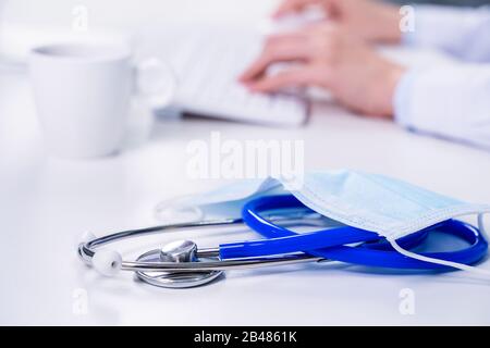Geschäftskonzept - Junge Ärztin, die mit Computer im Büro arbeitet, elektronische Krankenakte tippt, weißer Tischhintergrund, Nahaufnahme, Kopie Stockfoto