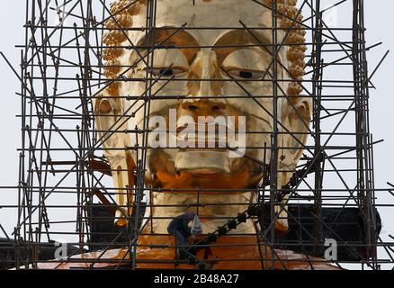 Nakhon Sawan, Thailand. März 2020. Ein Arbeiter sitzt während der Renovierung im buddhistischen Park in Nakhon Sawan auf einem Gerüst bei einer riesigen Statue des Buddha. Credit: Sopa Images Limited/Alamy Live News Stockfoto