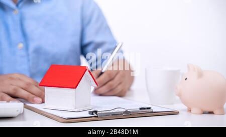 Geschäftskonzept - Der Junge Asiat in blauem Hemd berechnet, unterzeichnet den Vertrag über den Kauf einer Hauskreditzahlung, die Zahlung von Versicherungen, Steuern, Nahaufnahme. Stockfoto