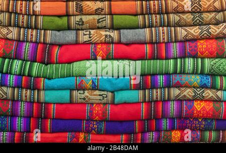 Ein Haufen farbenfroher Andentextilien, fotografiert auf dem lokalen Kunsthandwerksmarkt von Cusco, Peru Stockfoto