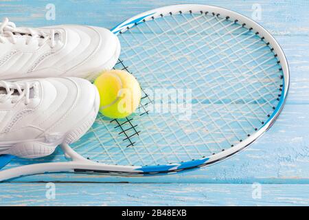 Tennisschläger mit Ball und Turnschuhen, auf hellem Hintergrund. Fotografiert im Studio Stockfoto