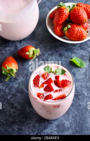 Erdbeerjoghurt mit frischen Beeren aus Glas auf blauem Steingrund. Gesundes Essen- und Getränkekonzept. Stockfoto