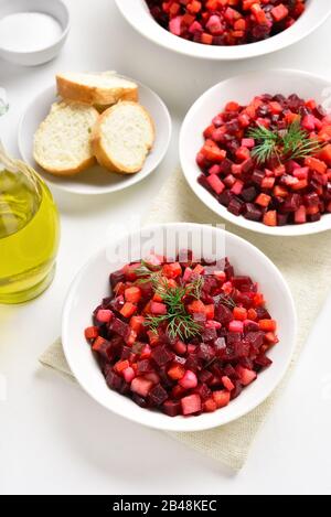 Rübensalat in der Schüssel. Gesunder Detox-Salat mit Rote Bete, Kartoffel, Karotten, Pickeln. Vegetarisches veganes Essen über weißem Steinhintergrund. Stockfoto