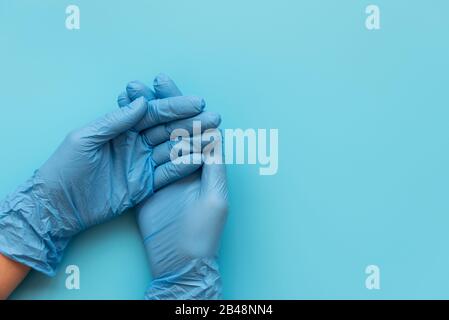 Hände von Sanitäter tragen blaue Latexhandschuhe auf blauem Hintergrund. Schutzkonzept Stockfoto