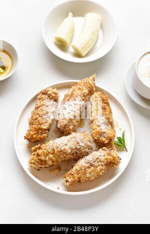 Frittierte Bananen auf die Platte über der weißen Stein Hintergrund. Leckere Dessert von Gebratene Bananen im asiatischen Stil. Stockfoto