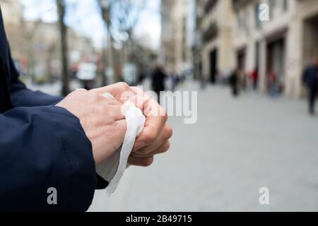 Nahaufnahme eines kaukasischen Mannes auf der Straße, der seine Hände mit einem feuchten Tuch desinfiziert Stockfoto