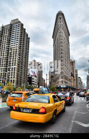 New YORK CITY, USA - 18. OKTOBER 2014: Gelbes Taxi- und Flatiron-Gebäude an der Fifth Avenue av in Manhattan. Flatiron ist ein ikonisches Buiding von NYC. Stockfoto