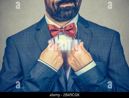 Zuschnitt junger Bräutigam in klassigem schwarzen Anzug mit weißem knöpftem Hemd, das die rote Krawatte verstellt. Hochzeitsvorbereitungen. Nahaufnahme Porträt von Mixed Race Be Stockfoto