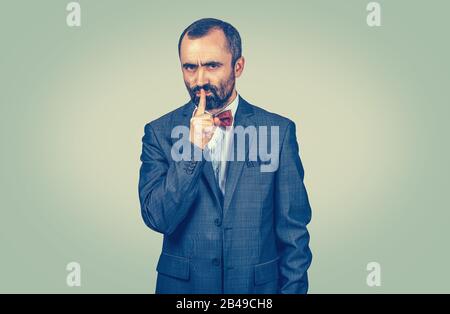 Reifer, gutaussehender Mann, der Shhh leise, schweigend, geheime Geste gibt. Nahaufnahmen von Mixed Race Bärtiermodell lateinamerikanischer Kerl isoliert auf hellem Gre Stockfoto