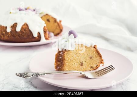 Glasierter osterkuchen mit Blumen und kleinen Schokoladeneiern, Süßigkeiten auf weißem Marmorhintergrund. Frohe Ostern. Stockfoto
