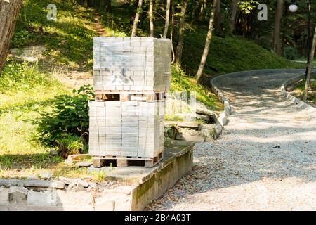 Pflasterstapel aus Beton auf einer Holzpalette. Blöcke zum Pflastern eines Gehwegs im Park. Stockfoto