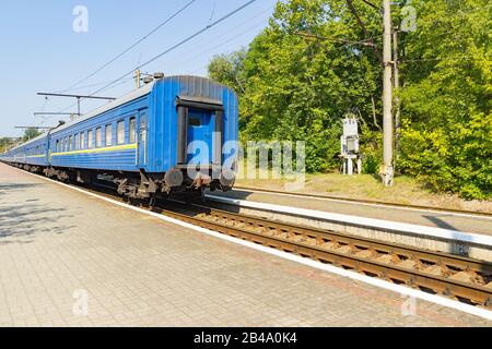 Der alte blaue Zug verlässt das Bahnhaus am Bahnhof. Stockfoto