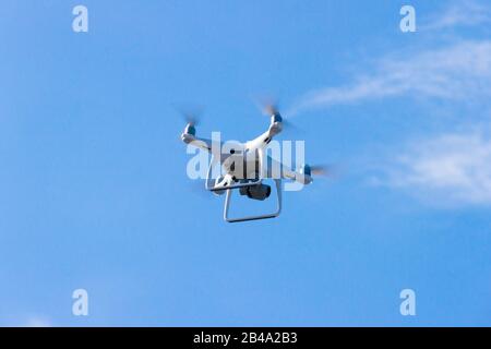 Quadcopter-Drohne flieht in den blauen Himmel. Unbemanntes Luftfahrzeug. Ferngesteuerte Videoaufnahmen aus großer Höhe. Moderne Digitalkamera. Stockfoto