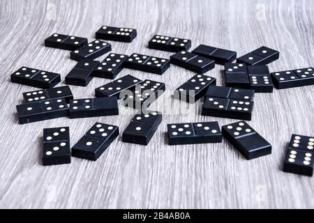 Schwarze Dominoos auf Holzhintergrund, Closeup verstreute Dominosteine auf einem grauen Holztisch. Brettspiel Stockfoto