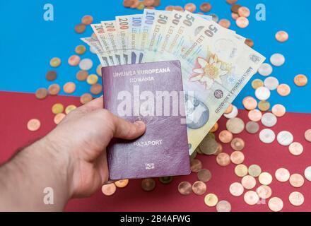 Rumänisches Konzept. Der rumänische Pass und die rumänischen Banknoten/Münzen auf blauem und rotem Hintergrund. Kolosseup des rumänischen Passes und der rumänischen Währung Stockfoto