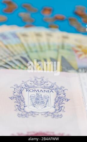 Rumänisches Konzept. Der rumänische Pass und die rumänischen Banknoten/Münzen auf blauem und rotem Hintergrund. Kolosseup des rumänischen Passes und der rumänischen Währung Stockfoto