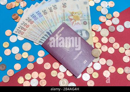 Rumänisches Konzept. Der rumänische Pass und die rumänischen Banknoten/Münzen auf blauem und rotem Hintergrund. Kolosseup des rumänischen Passes und der rumänischen Währung Stockfoto