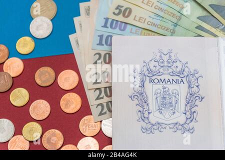 Rumänisches Konzept. Der rumänische Pass und die rumänischen Banknoten/Münzen auf blauem und rotem Hintergrund. Kolosseup des rumänischen Passes und der rumänischen Währung Stockfoto