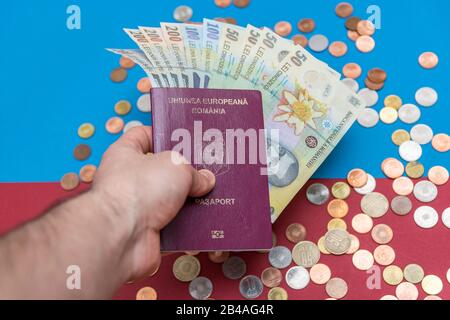 Rumänisches Konzept. Der rumänische Pass und die rumänischen Banknoten/Münzen auf blauem und rotem Hintergrund. Kolosseup des rumänischen Passes und der rumänischen Währung Stockfoto