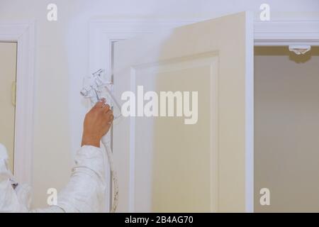 Handwerker seine Hand das Gemälde eine Spritzpistole, die eine Holztür lackiert Stockfoto