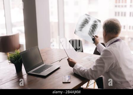 Erfahrener Oberarzt arbeitet mit medizinischen Dokumenten Stockfoto