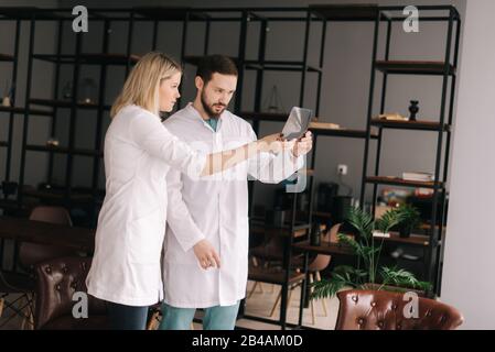 Das Ärzteteam zweier junger Ärzte diskutiert die Röntgenaufnahme des Patienten im Besprechungsraum Stockfoto