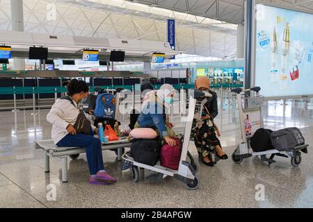 Hongkong, China. März 2020. Reisende, die Gesichtsmasken als Vorsichtsmaßnahme gegen den Ausbruch von Coronavirus tragen, warten in der Abflughalle des internationalen Flughafens Hongkong. Da sich das Coronavirus (Covid-19) weiterhin auf der ganzen Welt ausbreitet, haben viele Länder die Reisebeschränkungen verschärft. Credit: Sopa Images Limited/Alamy Live News Stockfoto