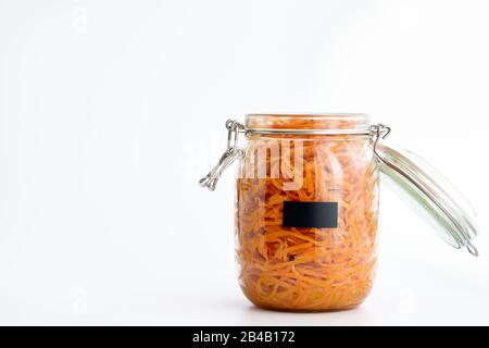 500 Gramm würziger koreanischer Karottensalat mit Öl, Knoblauch und schwarzem Pfeffer im Glasbecher. Nachhaltige Verpackung, weißer Hintergrund, hohe Auflösung Stockfoto