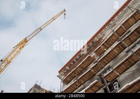 Pfeil des Krans und Teil des Gebäudes gegen den bewölkten Himmel Stockfoto