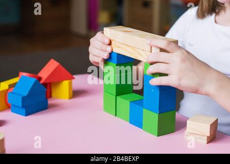 Das Kind sammelt den Designer baut ein Haus aus Holzwürfeln. Spielzeug aus umweltfreundlichen Materialien für Kinder. Null-West-Konzept Stockfoto