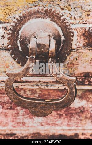 Interessanter Knocker an einer Tür mit schälender bunter Farbe. Stockfoto