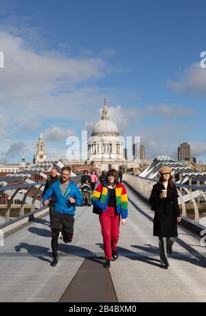 Menschen, die an einem sonnigen Tag im März die Millennium Bridge vor der St Pauls Cathedral überqueren, Londoner Innenstadt, London England UK Stockfoto