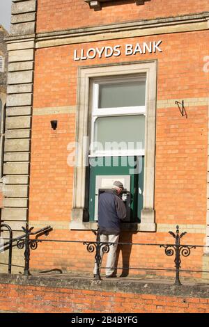 Ein Mann, der einen Lloyds Bank Cashpoint betreibt. England GB Stockfoto