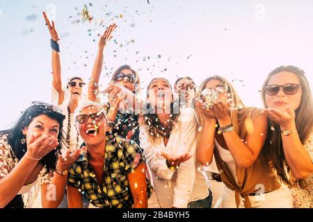 Menschen, die Spaß an Partyfeiern haben Freunde Konzept - Gruppe junger und erwachsener Frauen alle zusammen lachen blähende farbige Konfetti - Freundschaft und Lebensfreude mit gemischten aktiven Generationen Stockfoto