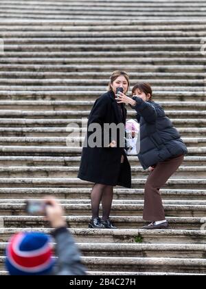 ROM, Italien - 04. März 2020: Zwei chinesische Touristen auf den Stufen von Trinità dei Monti auf der Piazza di Spagna, während sie gemeinsam ein selfie machen. Stockfoto