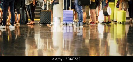 Gruppe von Personen, die auf ihrem Flug am Flughafen warten - Reisekonzept mit Passagieren, die darauf warten, mit ihrem Gepäck am Flugsteig einzusteigen oder einzuchecken - nicht erkennbar und gespiegelt auf dem Boden Stockfoto