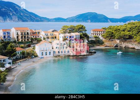 Süße blaue Meeresbucht vor dem Dorf Assos. Schöner Blick auf bunte Häuser in der Nähe der blau-türkisfarbenen, transparenten Bucht Lagune. Kefalonia, Griechenland. Stockfoto