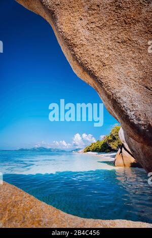 Eingerahmt von riesigen bizarren Felsbrocken aus Granit am berühmten Strand Anse Source d'Argent auf der Insel La Digue auf den Seychellen. Exotisches Konzept der paradiesischen Landschaft. Stockfoto