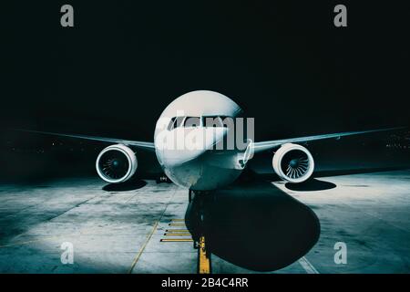 Flieger-Flugzeug am Terminal geparkt vom vorderen Cockpit-Rumpf, nachts auf der Landebahn. Stockfoto